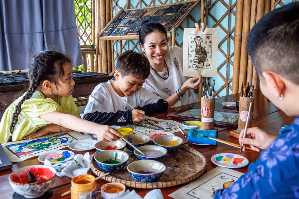 Des touristes prennent plaisir à réaliser eux-mêmes une peinture du village de Sinh. Photo : VNA