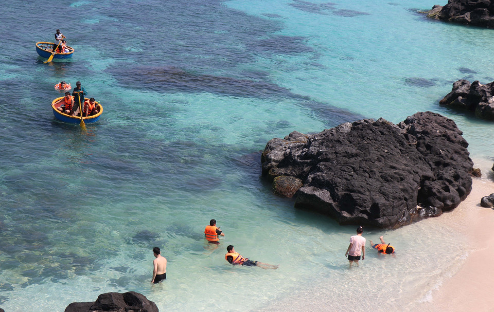 Des touristes font l'expérience du bateau-panier et se baignent dans l'eau bleue claire de l'île de Bé. Photo : Pham Cuong-VNA