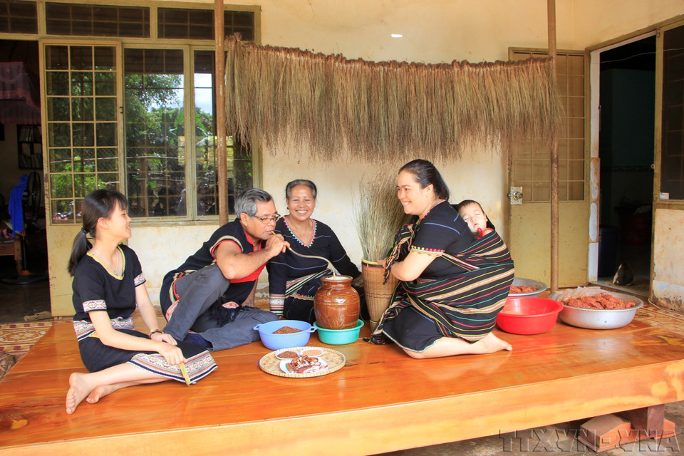 Dans les Hauts Plateaux du Centre, ce père de famille boit du «ruou cân» (alcool de riz à siroter avec un chalumeau de bambou) aux côtés de sa femme et de ses filles. Photo : Hông Diêp – VNA