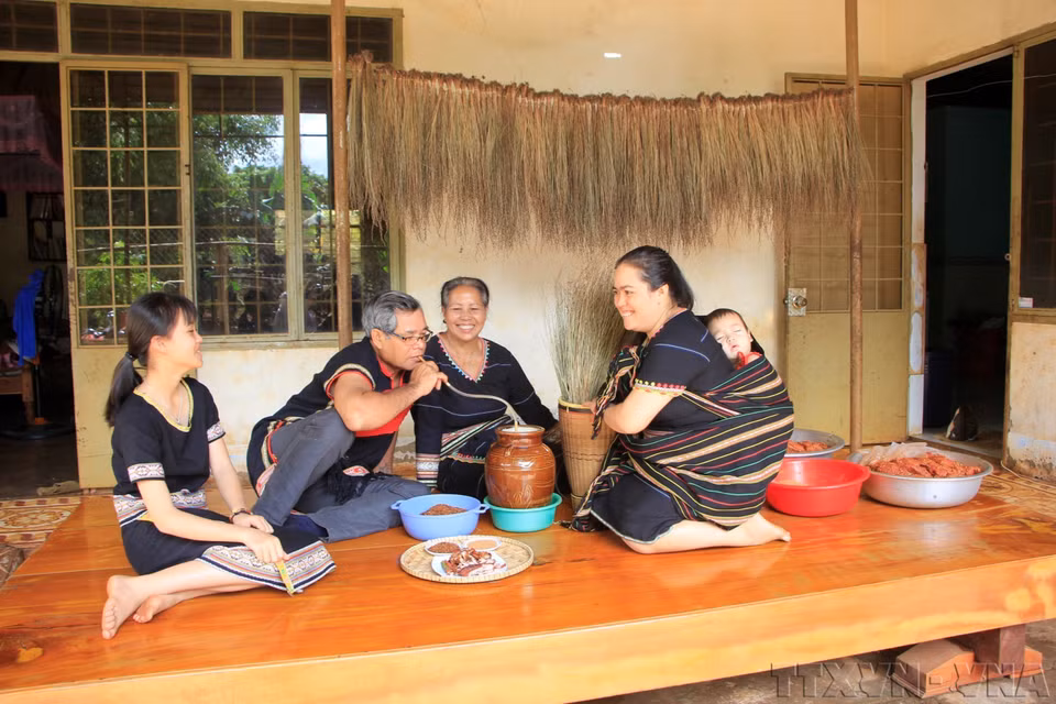 Dans les Hauts Plateaux du Centre, ce père de famille boit du «ruou cân» (alcool de riz à siroter avec un chalumeau de bambou) aux côtés de sa femme et de ses filles. Photo : Hông Diêp – VNA