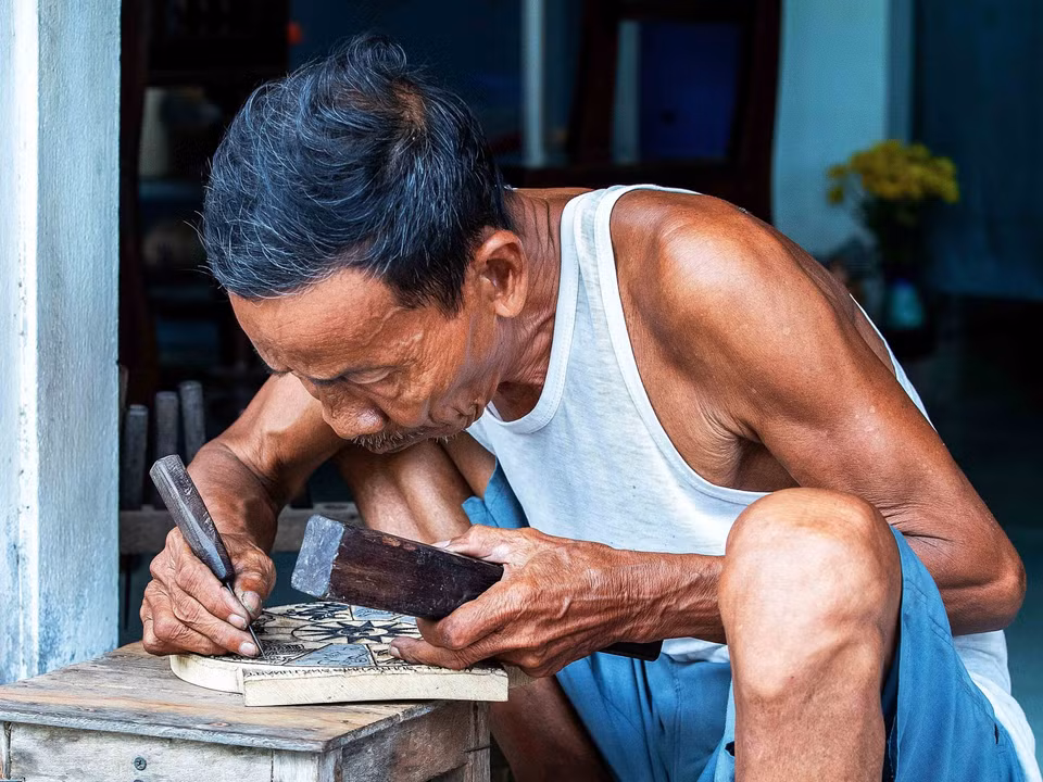 À 77 ans, l’artisan Ky Huu Phuoc incarne la neuvième génération d’une lignée familiale consacrée à l’art ancestral de la peinture du village de Sinh. Photo : VNA