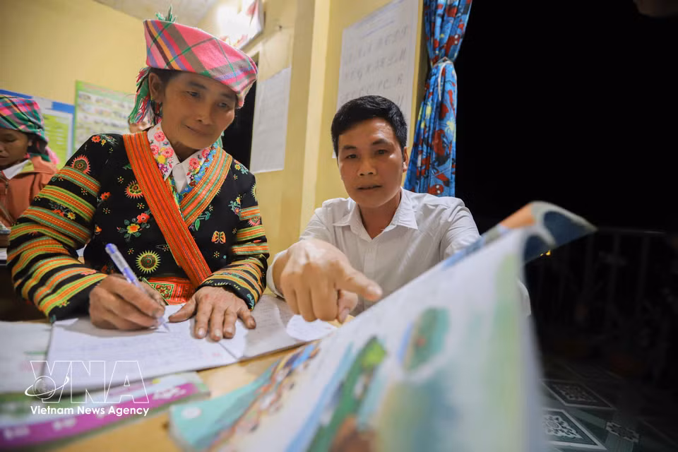 En poste au site scolaire de Lang Sang depuis plus de 15 ans, l’enseignant Lo Van Huan accompagne Song Thi Ly, la doyenne de la classe, âgée de près de 50 ans. Photo : VNA