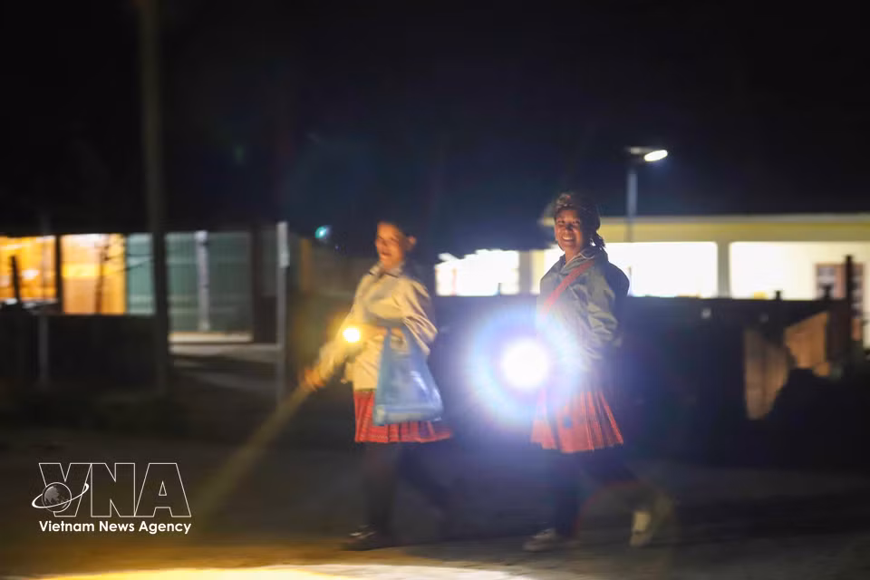 Munies chacune d’une lampe, elles prennent chaque soir le chemin de l’école pour apprendre à lire et à écrire. Photo : VNA