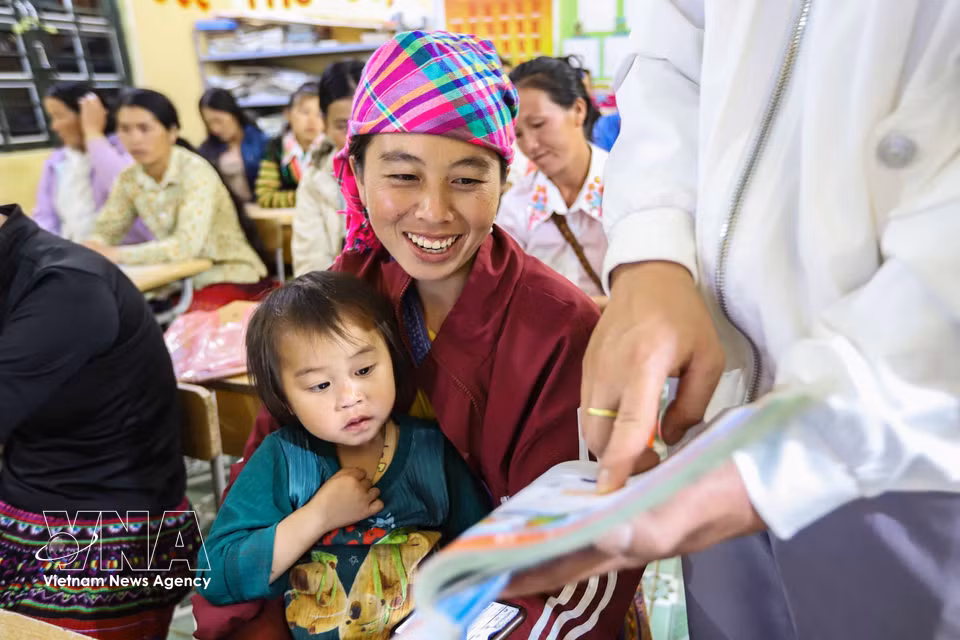 Hang Thi Cha, accompagnée de sa fille, s’exerce à la lecture avec son enseignant à l’aide d’un manuel de vietnamien de première année. Photo : VNA