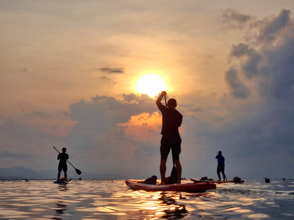 À Binh Son (Phan Rang - Thap Chàm), les touristes s'adonnent au SUP (Stand-Up Paddle), surfant sur les douces vagues de l'océan et profitant du spectacle du lever du soleil. Photo : VNA