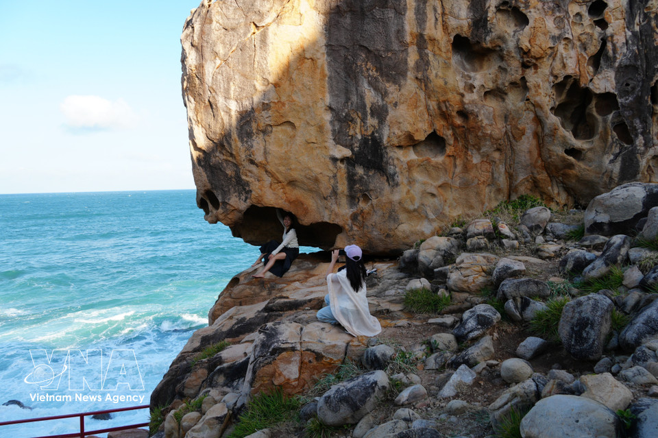 Des touristes immortalisent leur passage devant un rocher aux formes singulières à Hang Rai. Photo : VNA