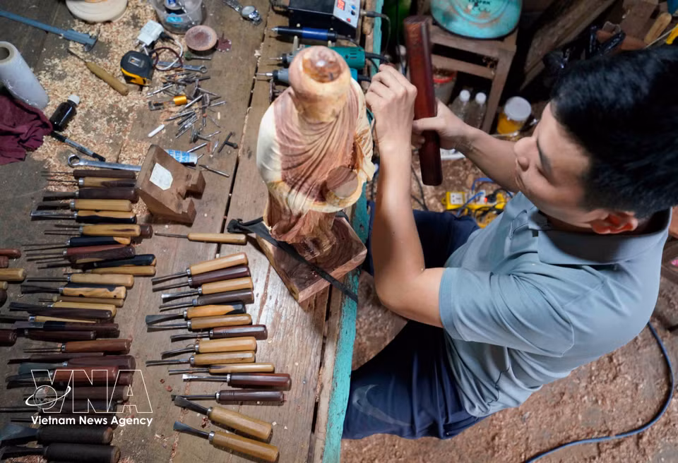 Par la précision de leurs gestes, les artisans donnent vie au bois à travers des œuvres délicatement sculptées aux motifs minutieusement travaillés. Photo : VNA
