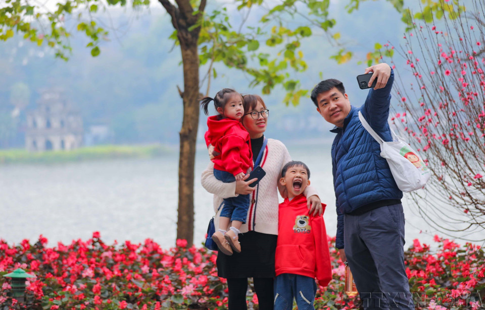 Une famille immortalise un moment de printemps au bord du lac Hoàn Kiêm (Epée restituée), à Hanoï, en janvier 2023. Photo : VNA
