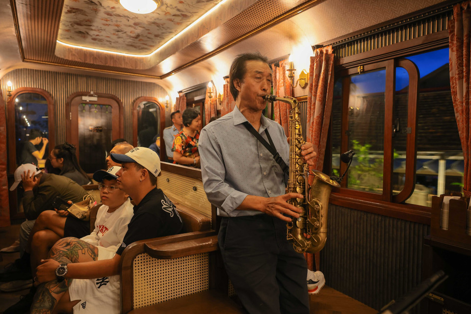 Le saxophoniste Phan Kim enchante les voyageurs avec des mélodies impeccables et des paysages poétiques, notamment à travers son interprétation de "Dà Lat au coucher du soleil". Sa musique crée une atmosphère envoûtante, ajoutant une couche de magie au voyage en train. Photo : VNA