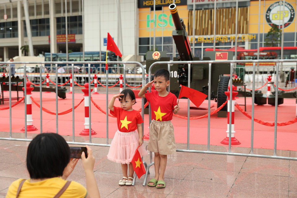 Des enfants, drapeaux nationaux en main, posent devant la batterie de canons. Photo : VNA