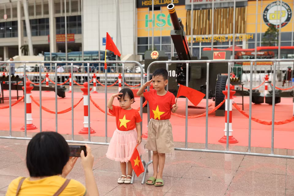 Des enfants, drapeaux nationaux en main, posent devant la batterie de canons. Photo : VNA