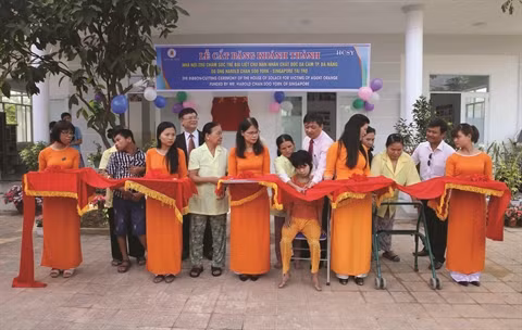 Des jeunes, victimes de l’agent orange, coupent le ruban d’inauguration de la maison financée par Harold Chan Soo York . Photo : VNA