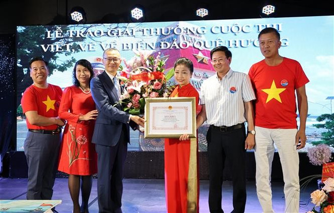 L’ambassadeur du Vietnam en Allemagne, Vu Quang Minh, remet un satisfecit à Bui Thi Thu Minh, cheffe du Comité de liaison des Vietnamiens en Europe « Pour la mer et les îles du Vietnam » et présidente du Club Truong Sa en Allemagne. Photo : VNA vna-potal-trao-giai-cuoc-thi-viet-va-ve-vi-bien-dao-que-huong-danh-cho-nguoi-viet-o-nuoc-ngoai-8121713.jpg