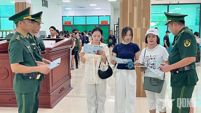 Les agents du Poste frontalier international de Lào Cai distribuent des dépliants de sensibilisation aux lois et règlements aux passagers franchissant la frontière. Photo: qdnd.vn tuyen-truyen.jpg