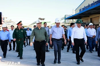 Le Premier ministre Pham Minh Chinh (chemise grise) visite des sites de production endommagés par le typhon Kalmaegi dans la zone économique de Nhon Hoi. Photo : VNA