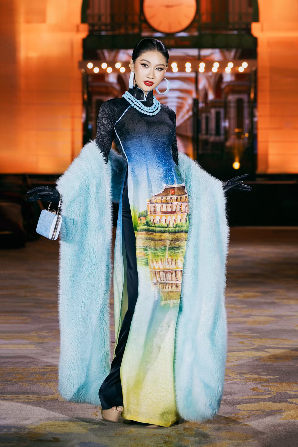 Chaque tenue met en valeur des œuvres architecturales et des paysages du monde entier. Sur la photo, Miss Cosmo Vietnam 2025, Nguyên Hoàng Phuong Linh, attire tous les regards dans un ao dài orné d’une image du quai de Nhà Rông.