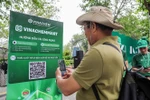 Les gens scannent directement le code QR de la plateforme de commerce électronique VinachemMart dans la rue piétonne du lac Hoàn Kiêm. Photo: VNA