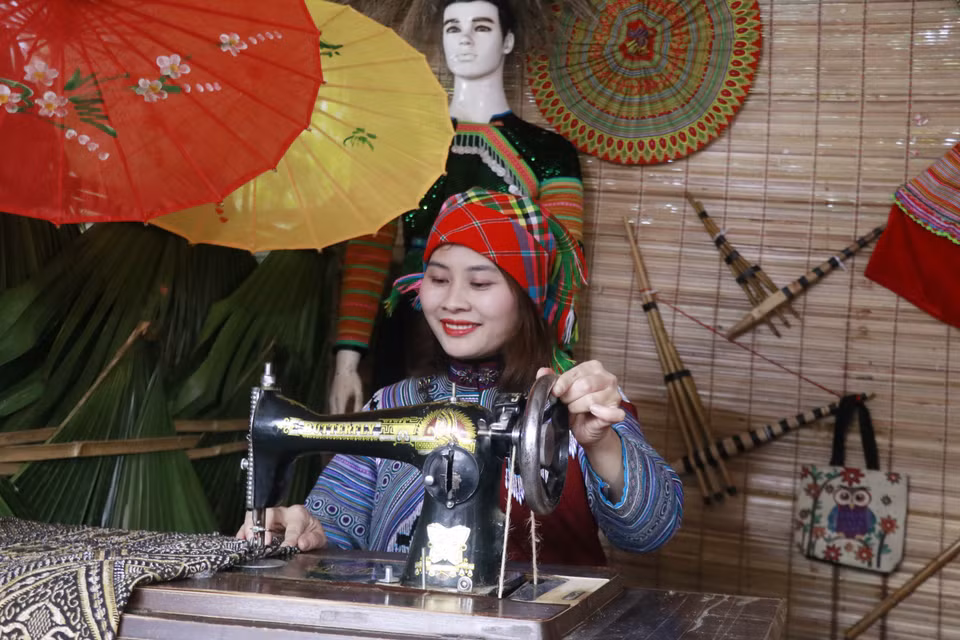 Fascinée par le savoir-faire ancestral, une touriste explore les secrets de la couture des costumes uniques de l'ethnie Mông. Photo: VNA
