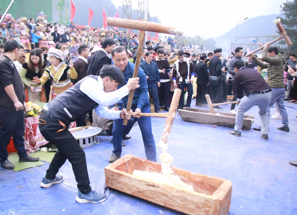 Touristes découvrant une étape de fabrication du gâteau de riz gluant du peuple Mông. Photo : VNA