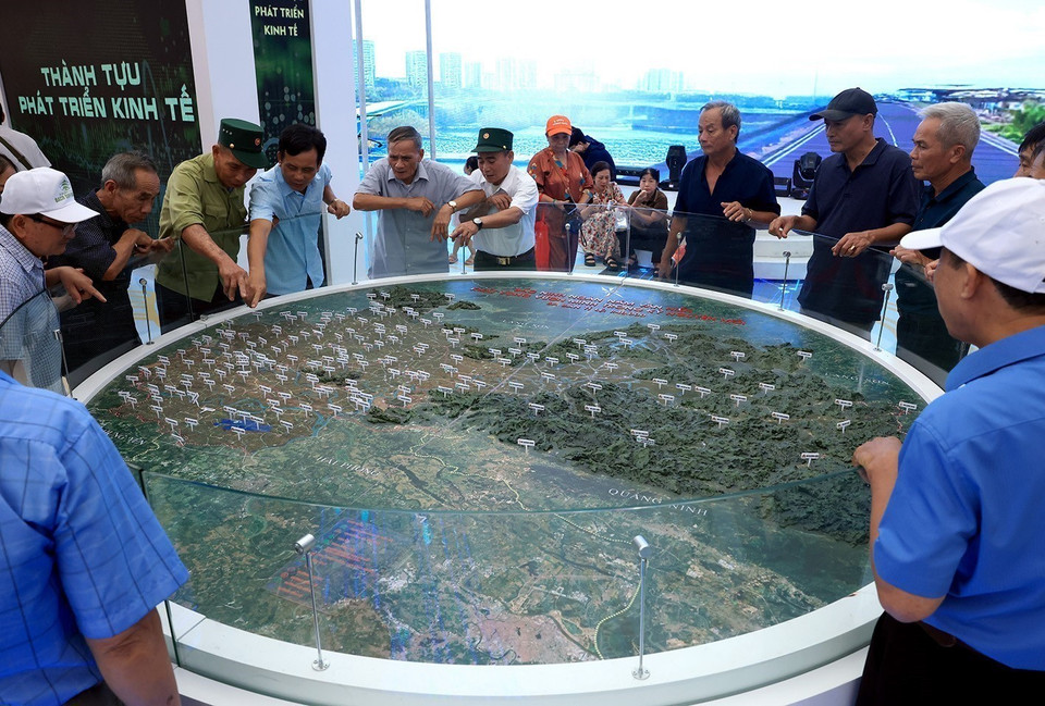 Des habitants observent la maquette de la nouvelle délimitation administrative après la fusion, au stand de la province de Bac Ninh.