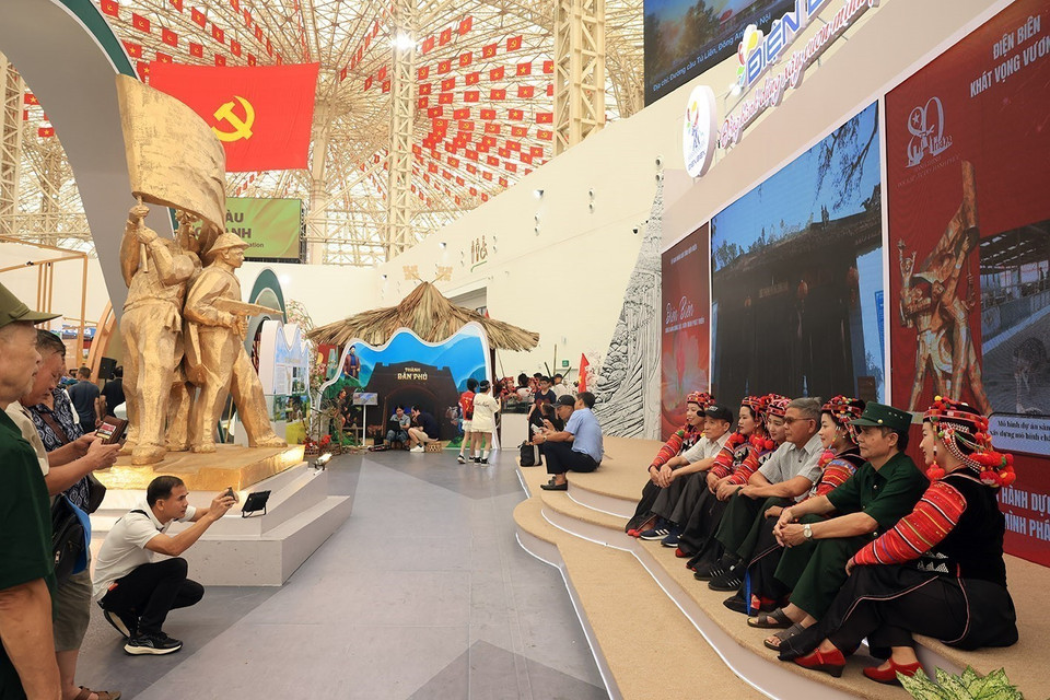 Des visiteurs prennent des photos souvenirs avec des membres de l’ethnie Hà Nhì au stand de la province de Diên Biên.