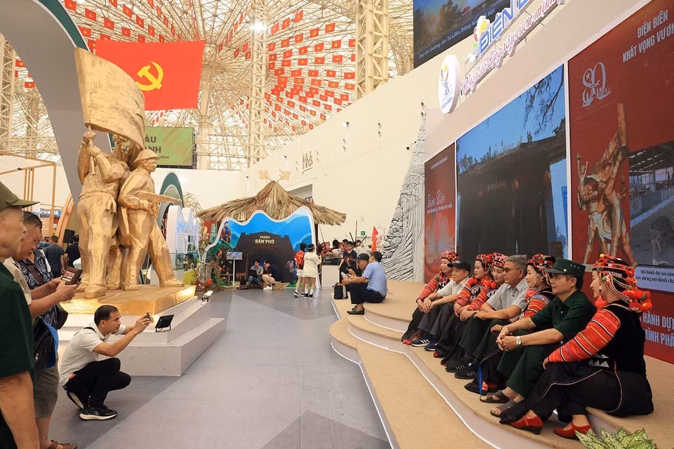Des visiteurs prennent des photos souvenirs avec des membres de l’ethnie Hà Nhì au stand de la province de Diên Biên.