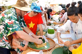Des touristes étrangers participent à la préparation de banh chung. Photo: VNA