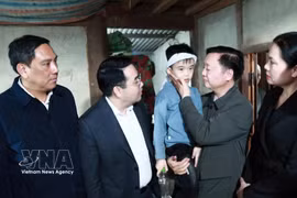 Le vice-Premier ministre Tran Hong Ha (2e de droite) rend visite à l'enfant rescapé du naufrage. Photo: VNA