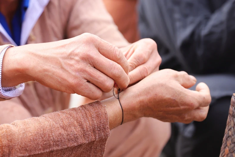 La personne à qui l’on attache le fil doit le garder au poignet toute l’année, sans jamais le retirer, jusqu’à la prochaine cérémonie d'accueil du premier tonnerre. Photo : VNA