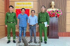 Doan Hong Hai (troisième à partir de gauche) remet un pangolin rare aux autorités de la commune de Bao Lam 1. Photo : VNA