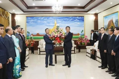 L'ambassadeur Nguyen Minh Tam remet des fleurs de félicitations du secrétaire général To Lam à la partie lao. Photo : VNA