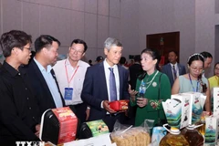 Nguyen Minh Vu, ambassadeur du Vietnam au Cambodge, et des entreprises cambodgiennes visitent le stand vietnamien. Photo : VNA