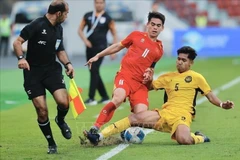 Un joueur malaisien U22 tente de bloquer le dribble de Khuat Van Khang. Photo : VNA 