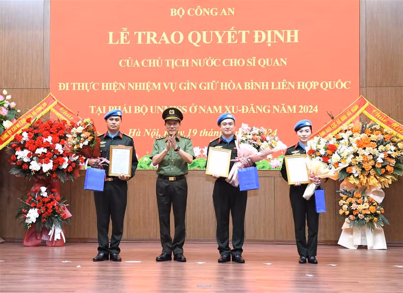 Le ministre de la Sécurité Publique, Luong Tam Quang, remet la décision du président à trois officiers. Photo: bocongan.gov.vn