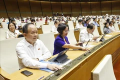 Dans le cadre de la 9ᵉ session de la 15ᵉ législature de l’Assemblée nationale, les députés votent l'approbation de la loi modifiant et complétant certains articles de la Loi sur l’organisation du Parquet populaire. Photo: VNA