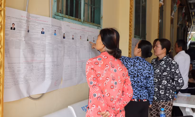 Des habitants khmers du hameau de Ngã Cạy, commune de Xà Phiên, consultent les informations sur les candidats aux élections de l’Assemblée nationale et des Conseils populaires affichées à la pagode Bôrâysarâychum. Photo : VNA.