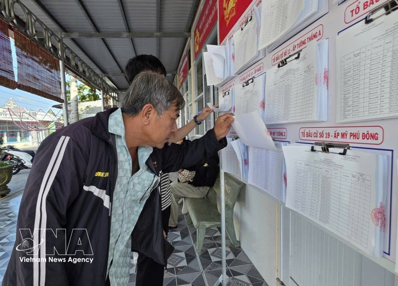 Des électeurs de la commune de Vĩnh Thanh, dans la province de Cà Mau, consultent les informations relatives aux élections et prennent connaissance du parcours ainsi que du programme d’action des candidats. Photo : VNA.
