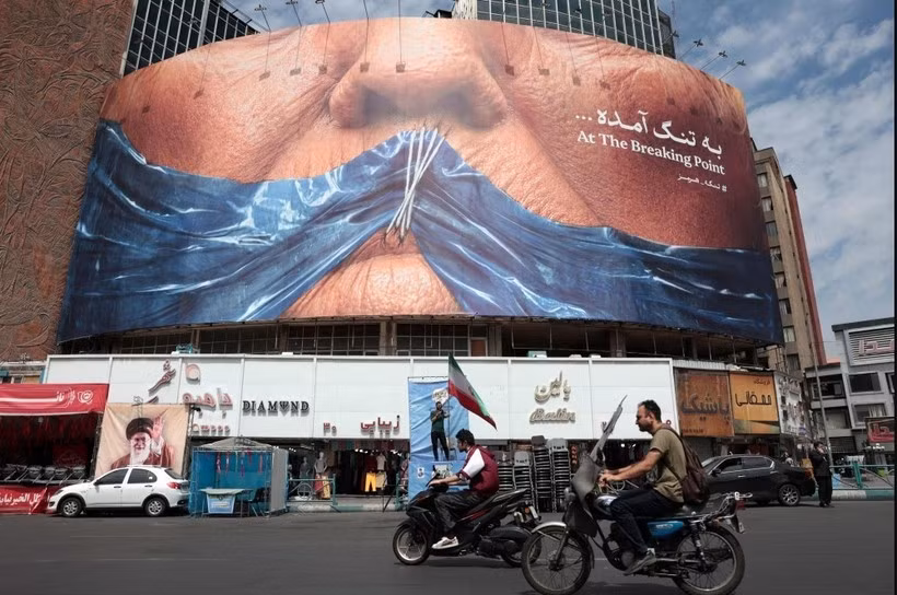 Des automobilistes passent devant un panneau d'affichage anti-américain faisant référence au président Donald Trump et au détroit d'Ormuz, place Valiasr à Téhéran, le 2 mai 2026. (Photo : AFP)