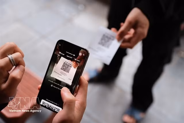 Un client effectue un paiement par QR code dans un café. Le ministère des Finances a proposé une nouvelle réglementation concernant les seuils de revenus imposables pour les entreprises à domicile. Photo : VNA