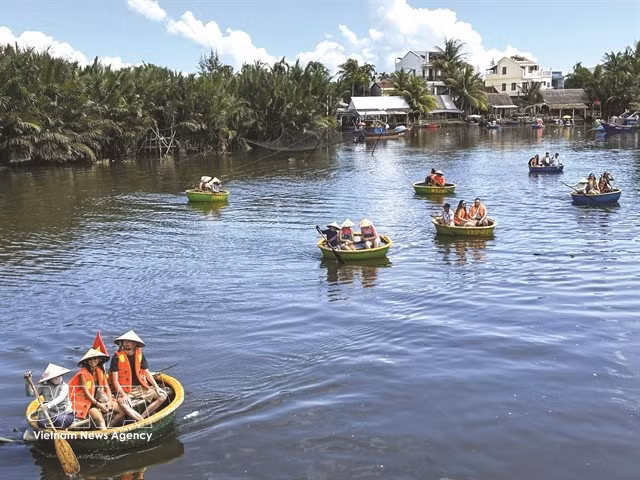 De nombreux touristes font des excursions en bateau autour du village de palmiers à nipa de Cẩm Thanh pour découvrir l'un des plus beaux villages du monde. Photo : VNA