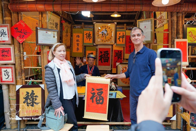 Des visiteurs internationaux participent à l’activité traditionnelle de demande de calligraphie en début d’année. (Photo : VNA)