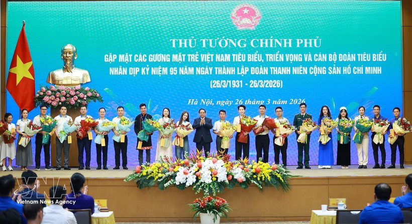 Le Premier ministre Pham Minh Chinh offre des fleurs de félicitations aux jeunes Vietnamiens exemplaires. Photo : VNA