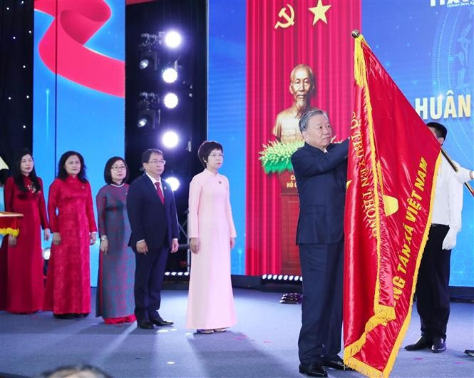 Le secrétaire général To Lam épingle l’Ordre de Hô Chi Minh sur le Drapeau traditionnel de la VNA. Photo : VNA