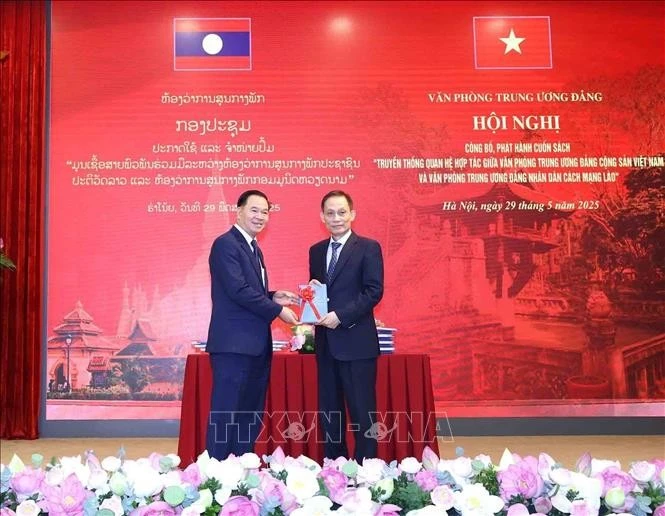 Le Hoai Trung (droite), secrétaire du Comité central du PCV et chef du Bureau du Comité central du PCV, offre un exemplaire du livre à Thongsalith Mangnomek, secrétaire du Comité central du PPRL et chef du Bureau du Comité central du PPRL. Photo : VNA