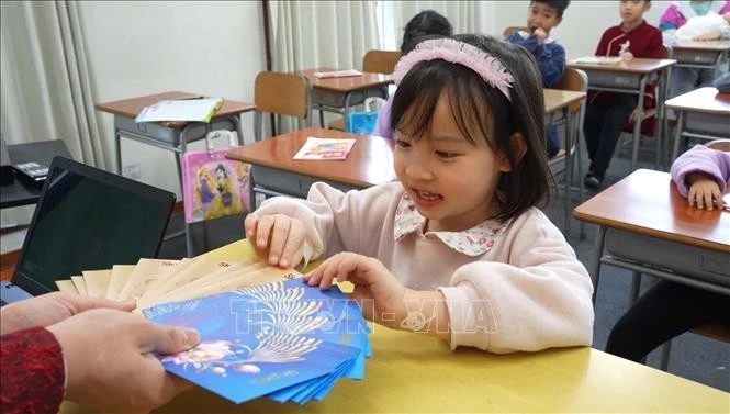 La petite Mai Chi, 5 ans, élève de l'école, est ravie de recevoir des étrennes du Nouvel An, selon la tradition du Têt vietnamien. Photo : VNA