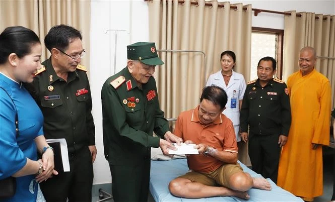 Le général Vo Van Chot, ancien commandant de la 324e division et ancien commandant adjoint de la Région militaire 4, remet le cadeau à un ancien combattant lao. Photo: VNA