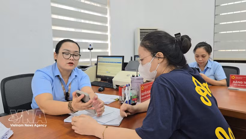 Des fonctionnaires du quartier de Mao Khe guident une citoyenne dans le dépôt en ligne de ses dossiers de certification sur le Portail national de la fonction publique. Photo : TTXVN