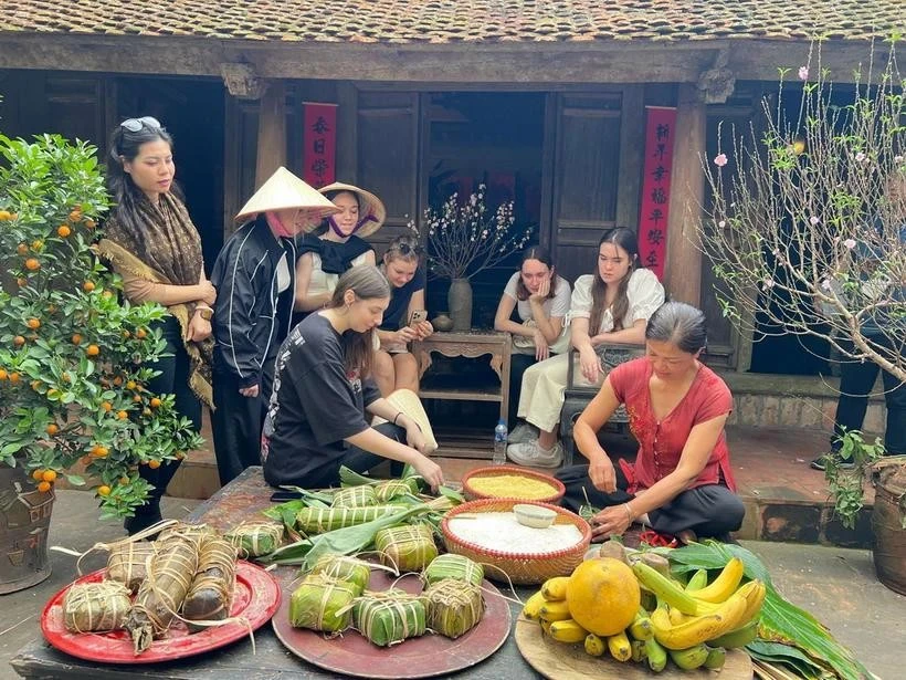 Des touristes étrangers essaient de confectionner des "banh chung" à l'ancien village de Duong Lam. Photo: VNA