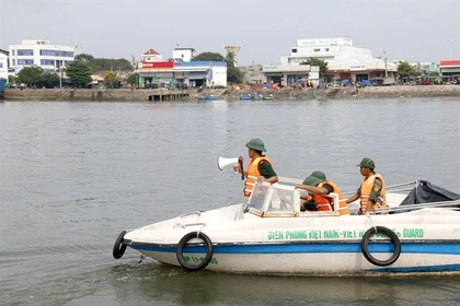 Un garde-frontière diffuse au haut-parleur l’interdiction de sorties en mer et exhorte les bateaux à se mettre à l’abri au port de Phan Thiêt, à Lâm Dông. Photo : VNA