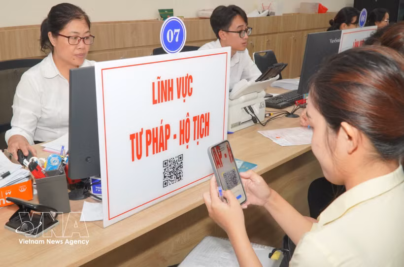 Des citoyens scannent des codes QR pour consulter les procédures et les démarches relatives aux questions judiciaires et d'état civil. Photo : VNA